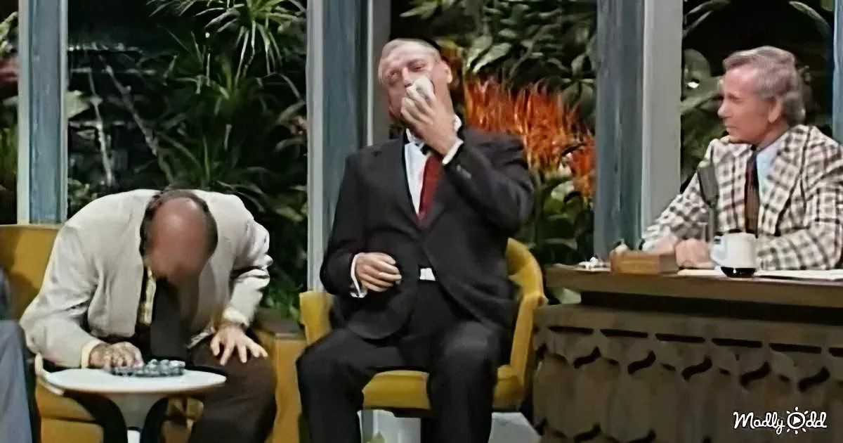 A man in a suit sits with a handkerchief to his nose, appearing distressed, while another bends over a table, and a third...