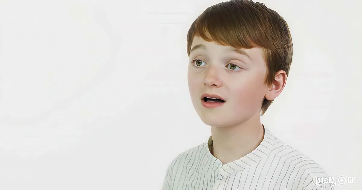 A young boy with short brown hair and a striped shirt looks surprised against a plain white background.