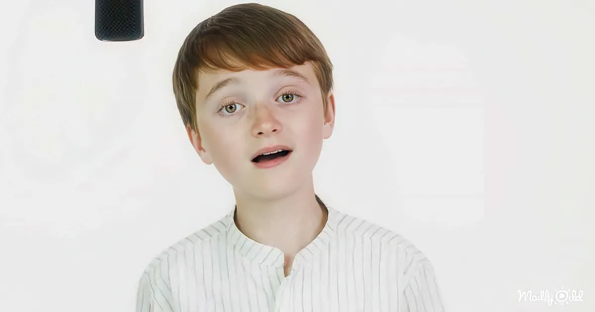 A young boy with short brown hair and a surprised expression, wearing a white striped shirt.
