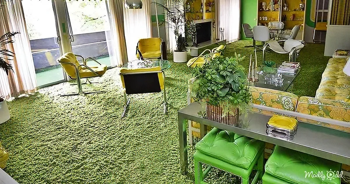 A retro living room with green carpet, yellow and green furniture, and a potted plant on a table.