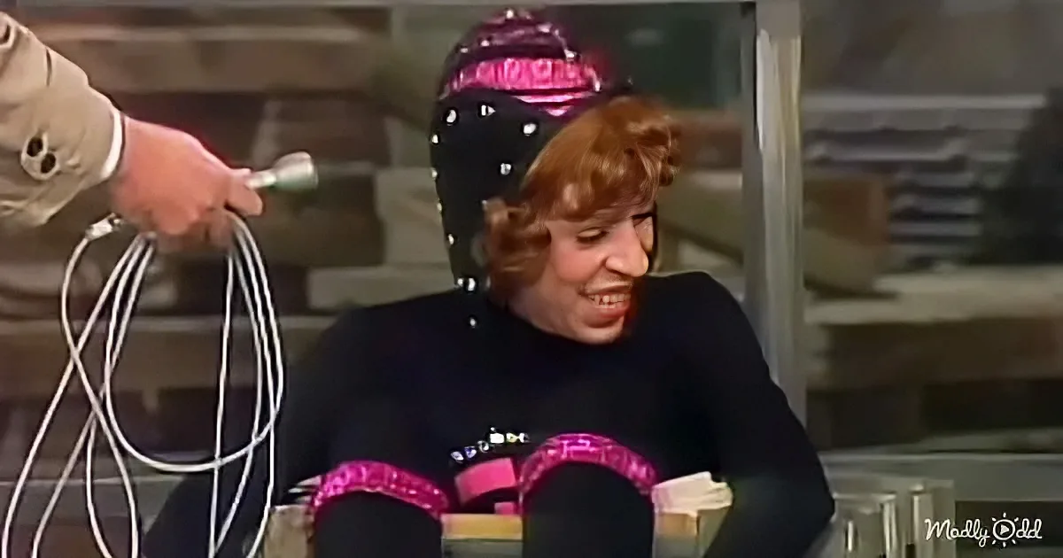 A person wearing a helmet and pink headband smiles while another hand holds a cord near them.