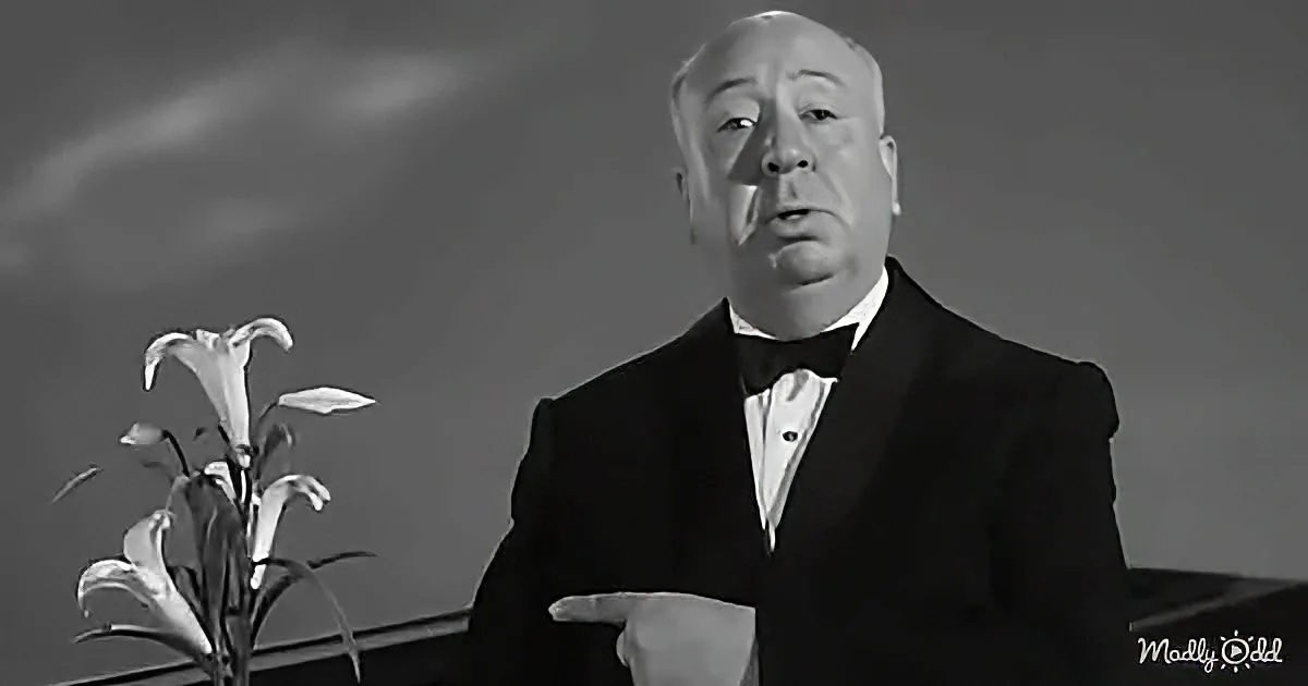 A man in a tuxedo points to the left, with a lily plant in the foreground.