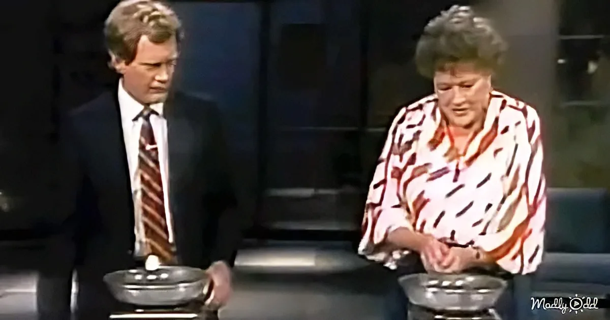A man in a suit and a woman in a patterned shirt are standing in front of bowls, possibly preparing or demonstrating...