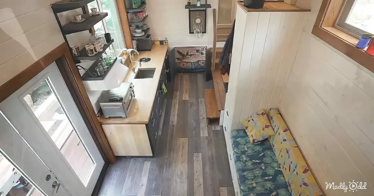 A cozy, compact living space with a kitchen, small bed, and wooden floors.