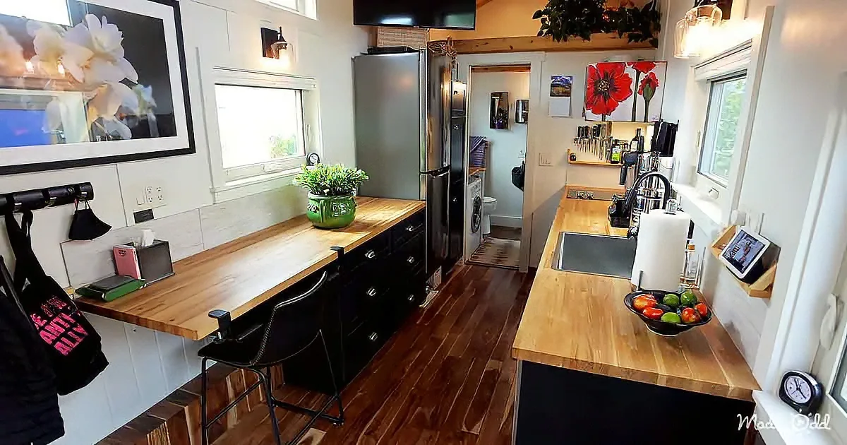 A cozy kitchen with wooden countertops, black cabinets, and a stainless steel refrigerator.