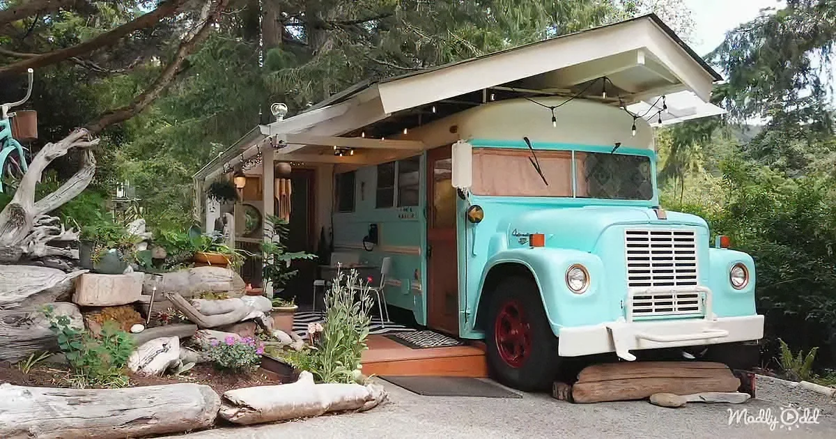 A turquoise vintage bus repurposed as a cozy home with a garden and outdoor seating.