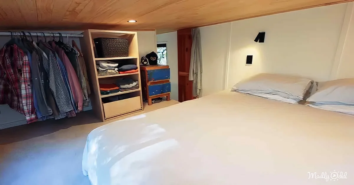 A neatly organized bedroom with a bed, clothes rack, shelves, and a small desk.