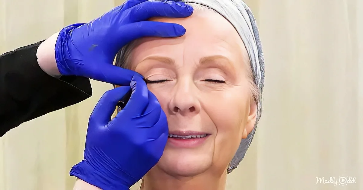 A woman receives a facial treatment with gloved hands adjusting her hair.