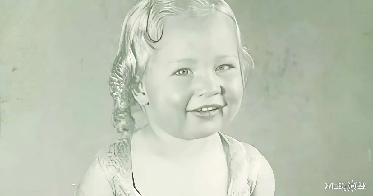 A smiling child with blonde hair in a black and white portrait.