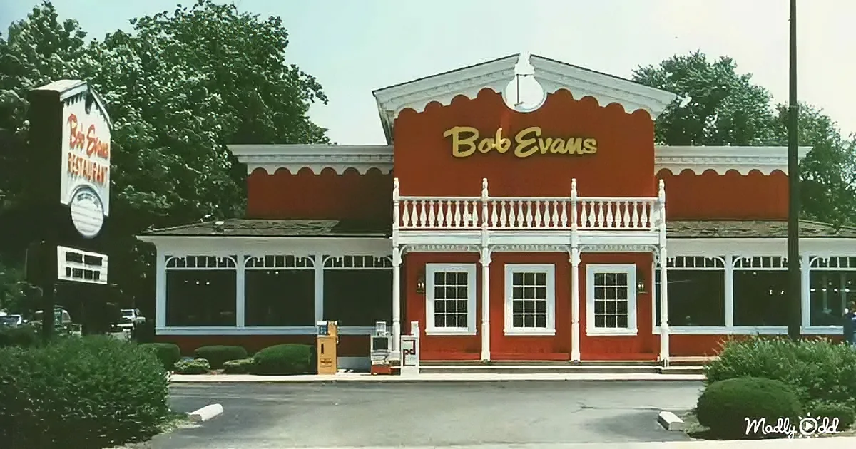 A Bob Evans Restaurant with a red facade and white trim, surrounded by greenery and a clear sky.