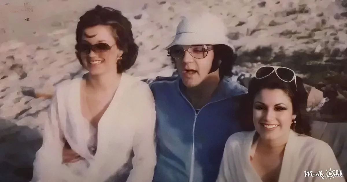 Three women smile outdoors, one in a white top, another in a blue jacket, and the third in a beige top, with a rocky...