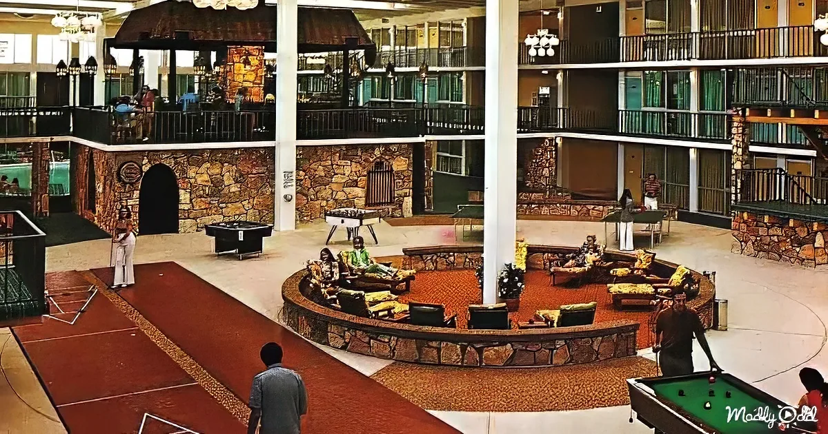 People relax in a spacious, multi-level hotel lobby with stone accents, pool tables, and a foosball table.