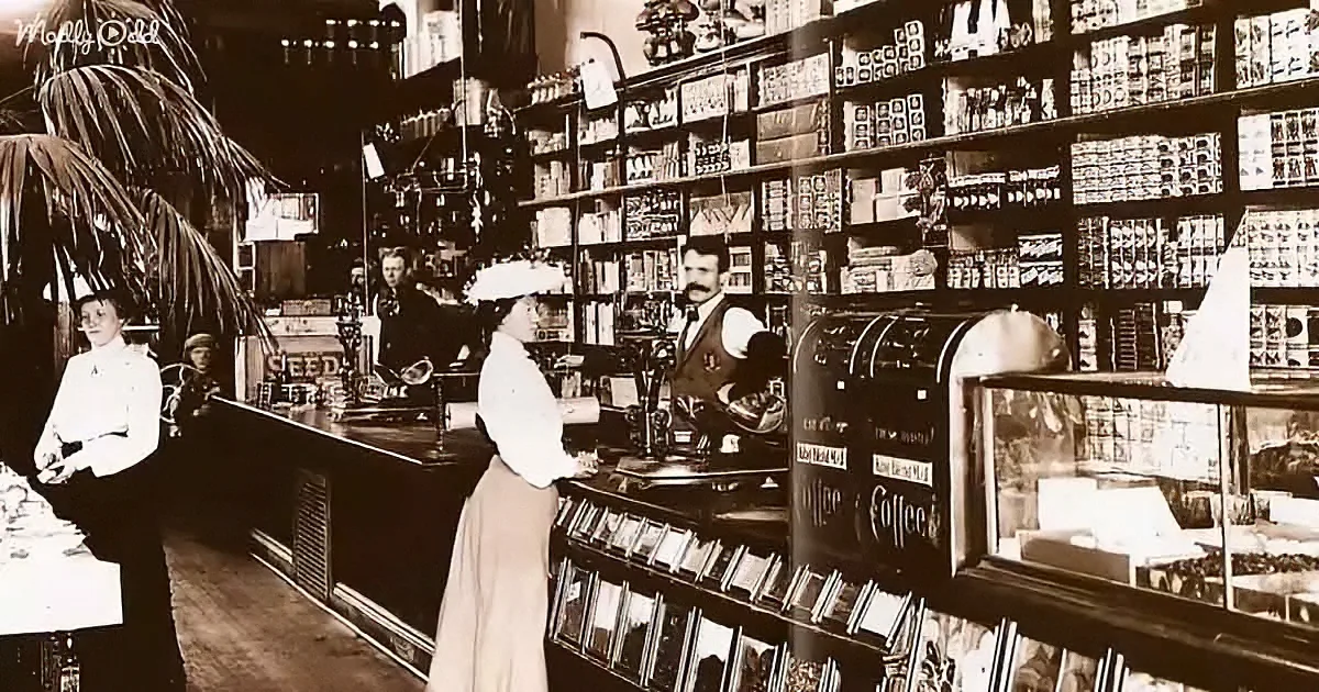 A vintage store scene with a woman in a white apron and hat serving a customer at a counter.