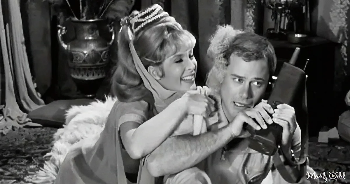 A woman in a fur dress hugs a man holding a phone, both appear surprised or amused.