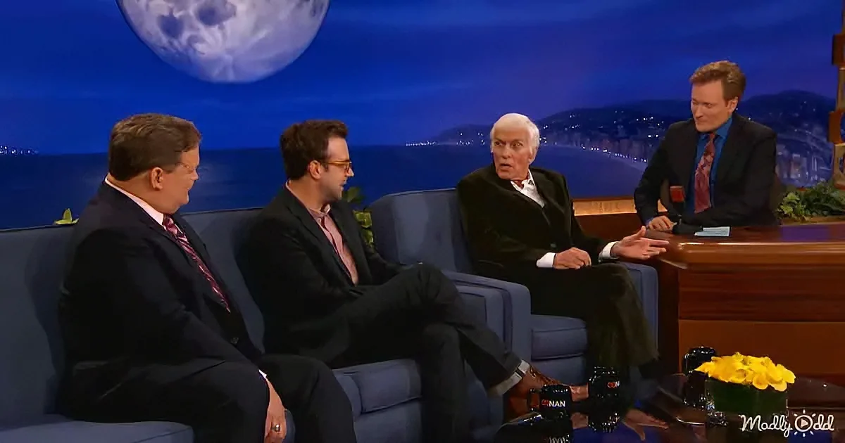 Conan O'Brien hosts a talk show with guests on a couch, featuring a night sky backdrop.