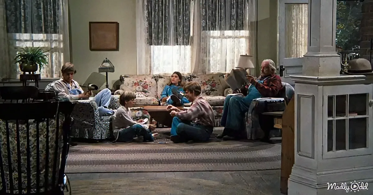 A family is gathered in a cozy living room, engaged in various activities around a floral-patterned sofa.