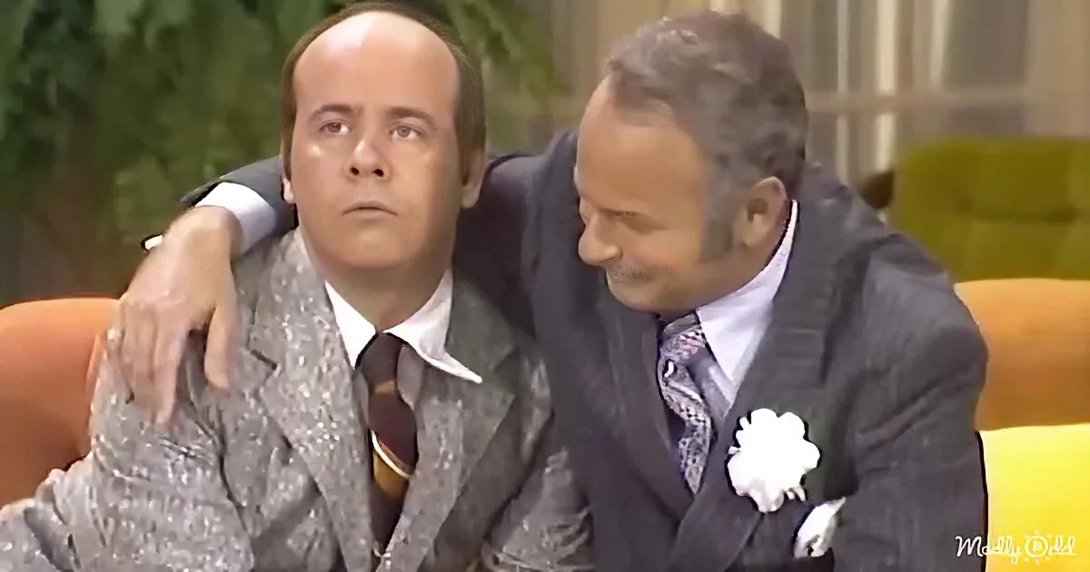 A man in a suit is being comforted by another man with a flower on his lapel.