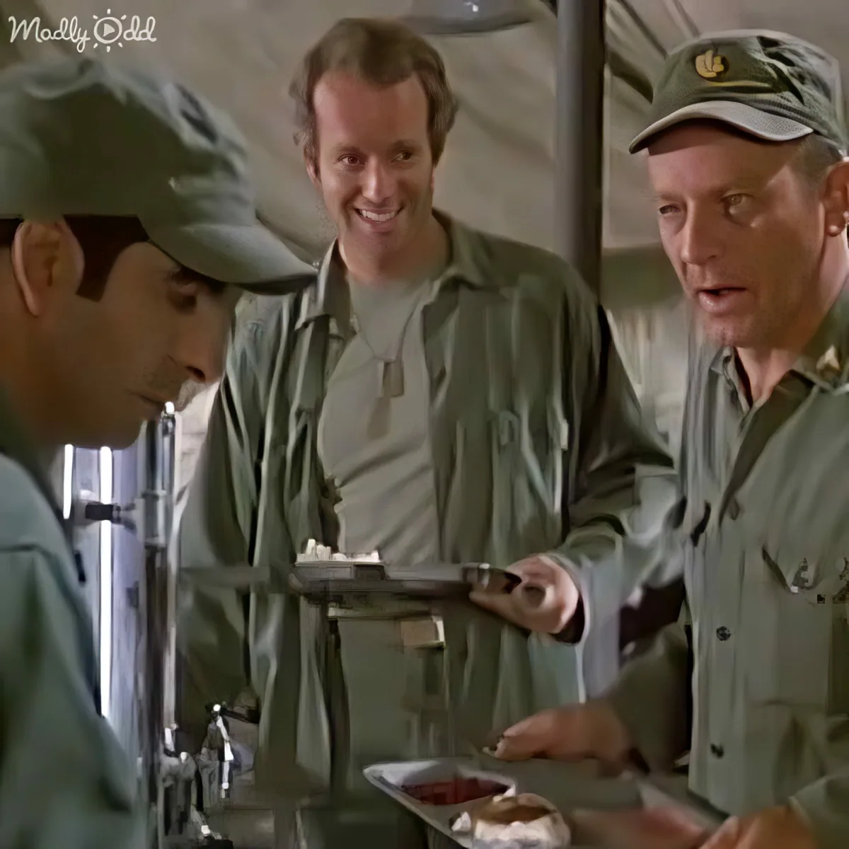 A man in a military uniform hands a tray of food to another man in a similar uniform.