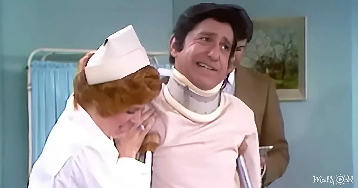 A nurse in a white uniform embraces a man in a white shirt and neck brace, both in a hospital setting.