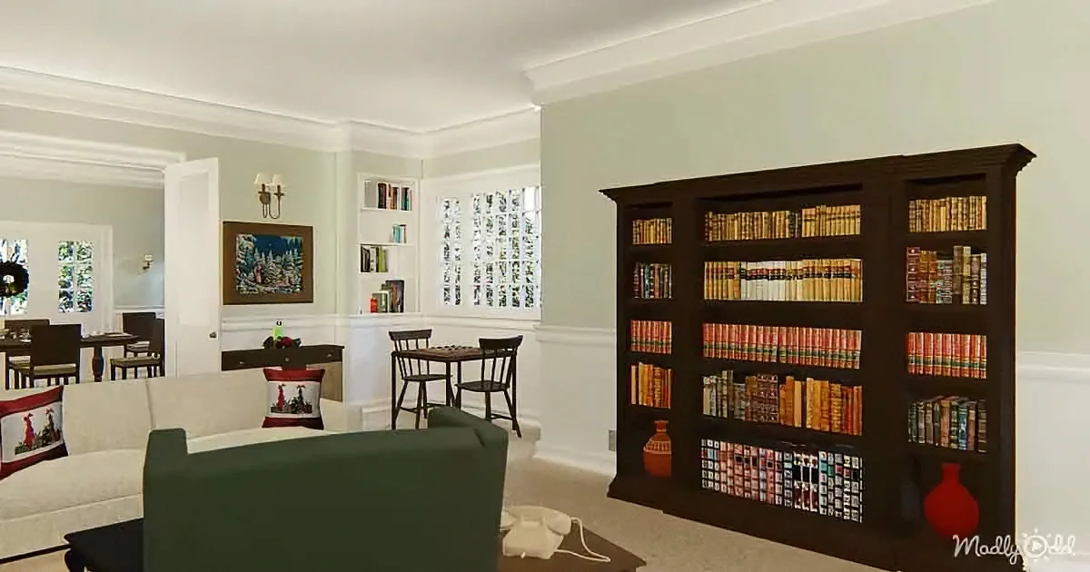 A cozy living room with a large bookshelf, white couch, and a small dining area in the background.
