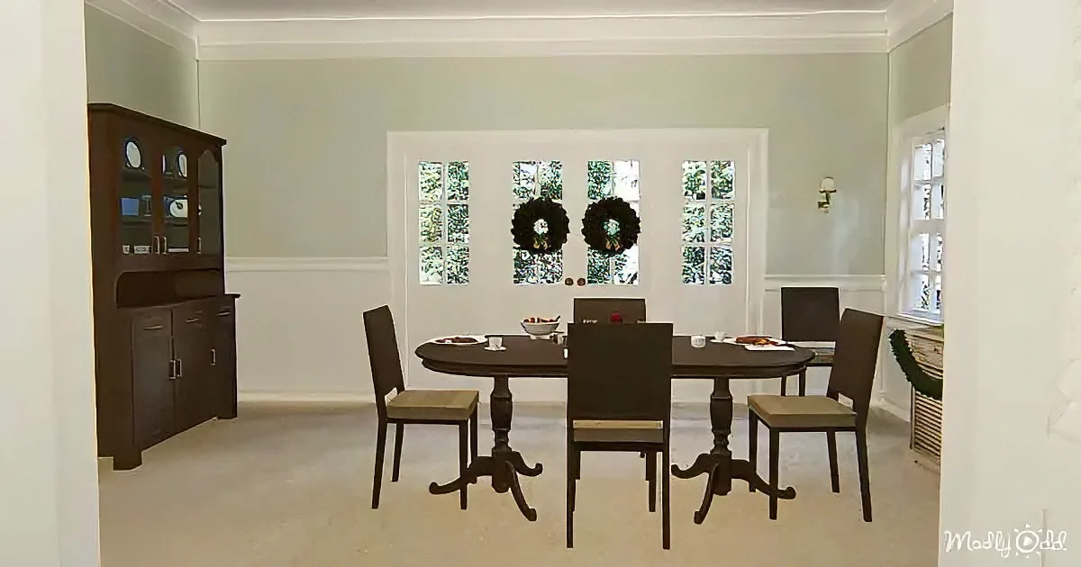 A dining room with a dark wood table, chairs, and a cabinet, decorated with wreaths on the windows.
