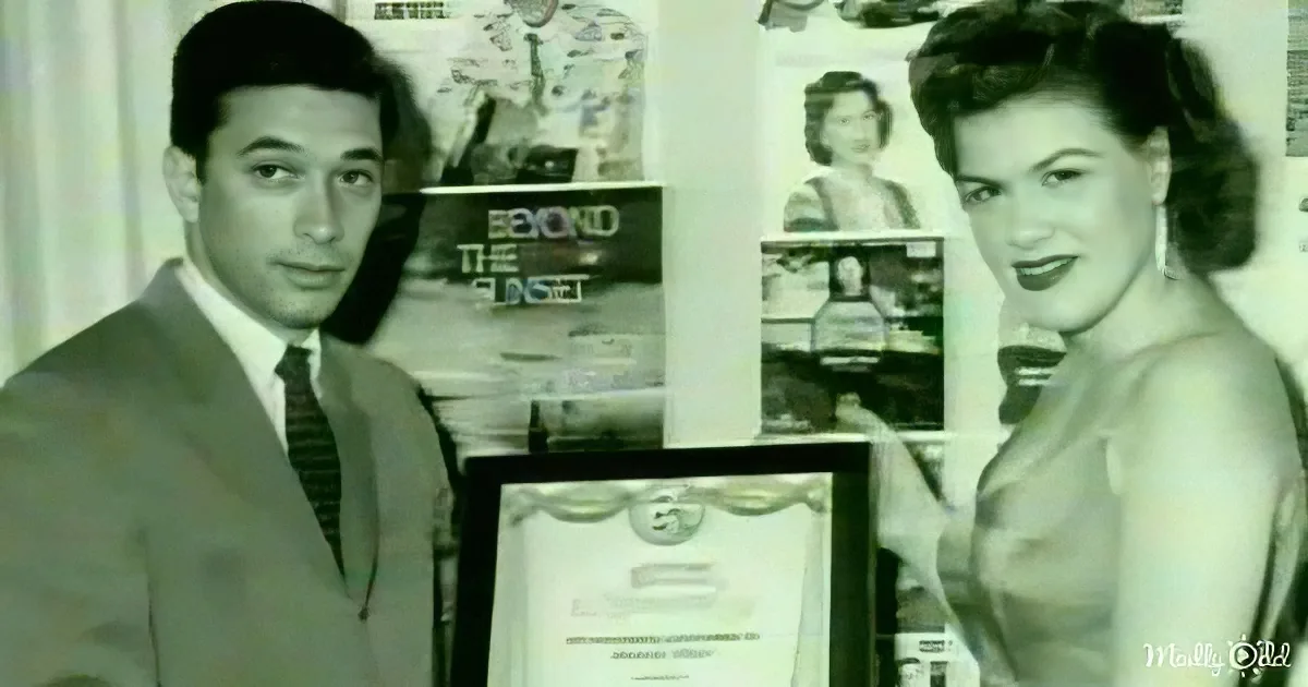 A man in a suit and tie stands next to a woman in a dress, both posing with a framed certificate.