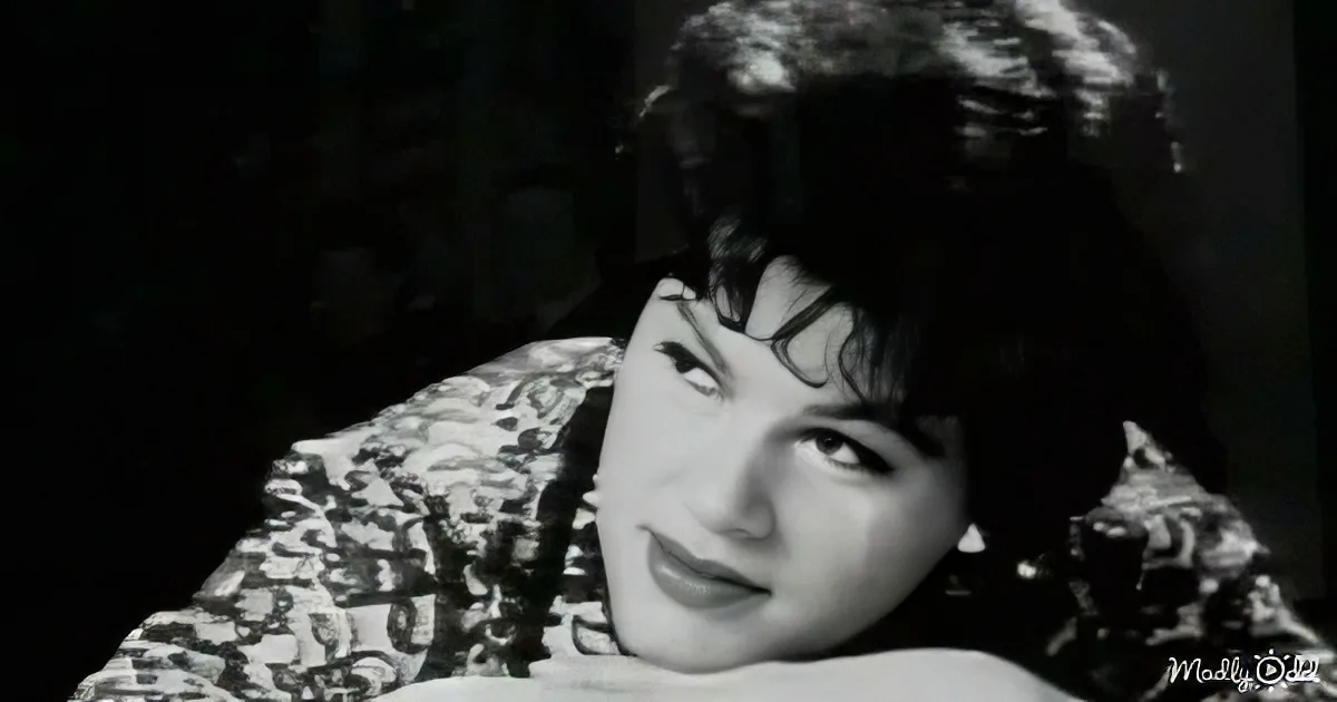 A woman with dark hair and a patterned garment, looking to the side with a serious expression.