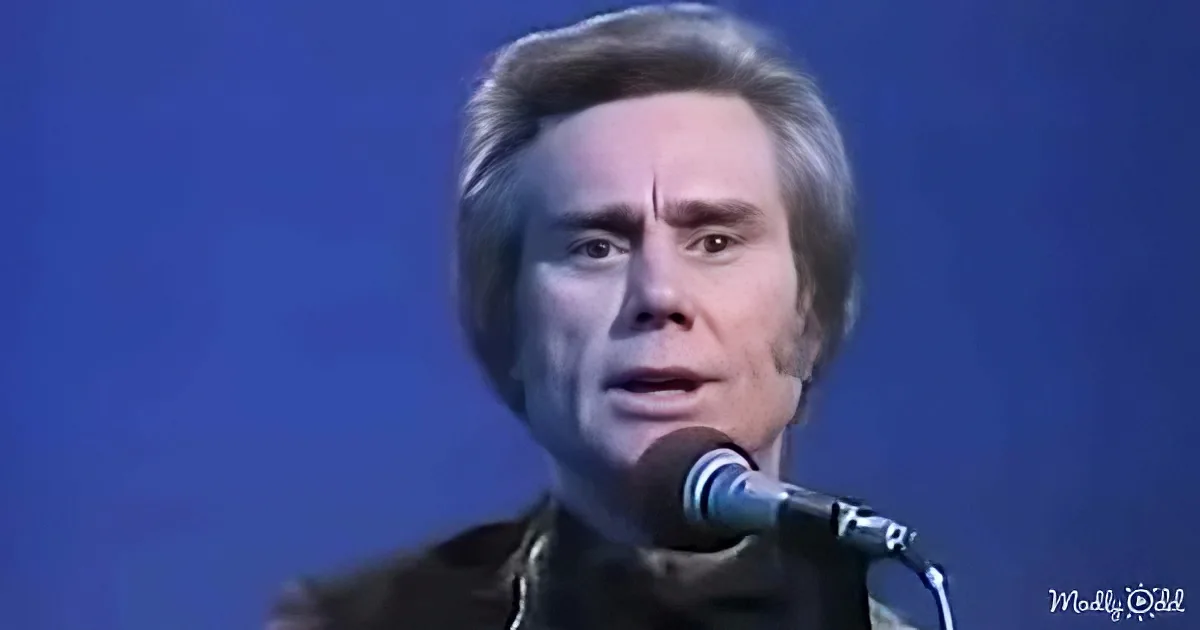 A man with light-colored hair and a dark outfit sings into a microphone against a blue background.