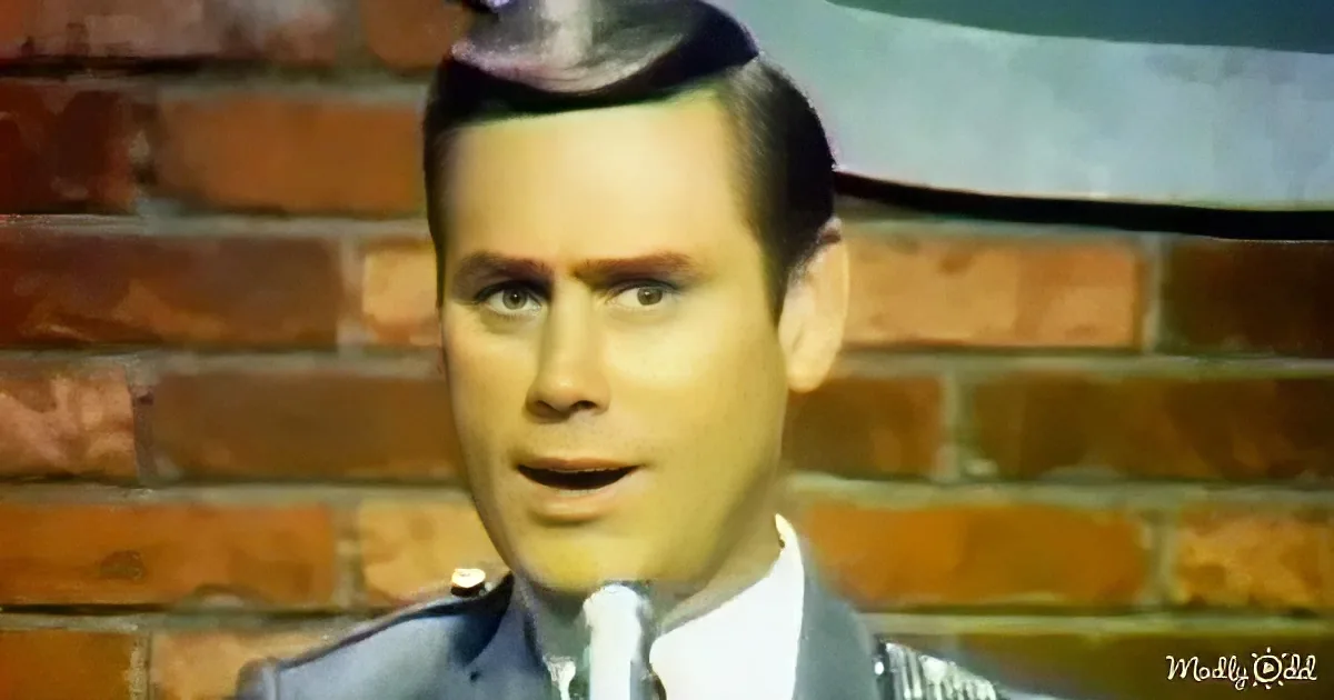 A man in a uniform with a hat is speaking in front of a brick wall.