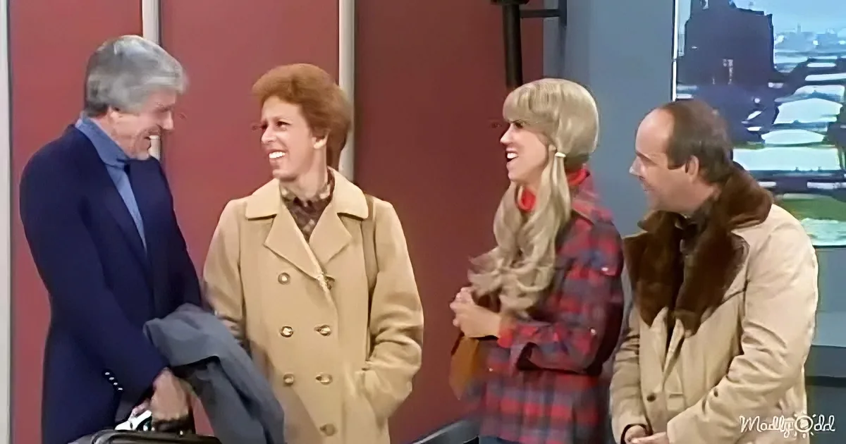 A man in a suit and a woman in a beige coat are laughing together, joined by two others in a casual setting.