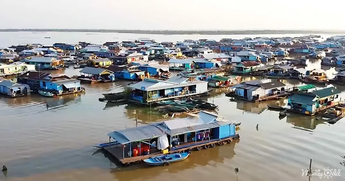 A cluster of colorful floating houses on calm water, with boats and structures densely packed.