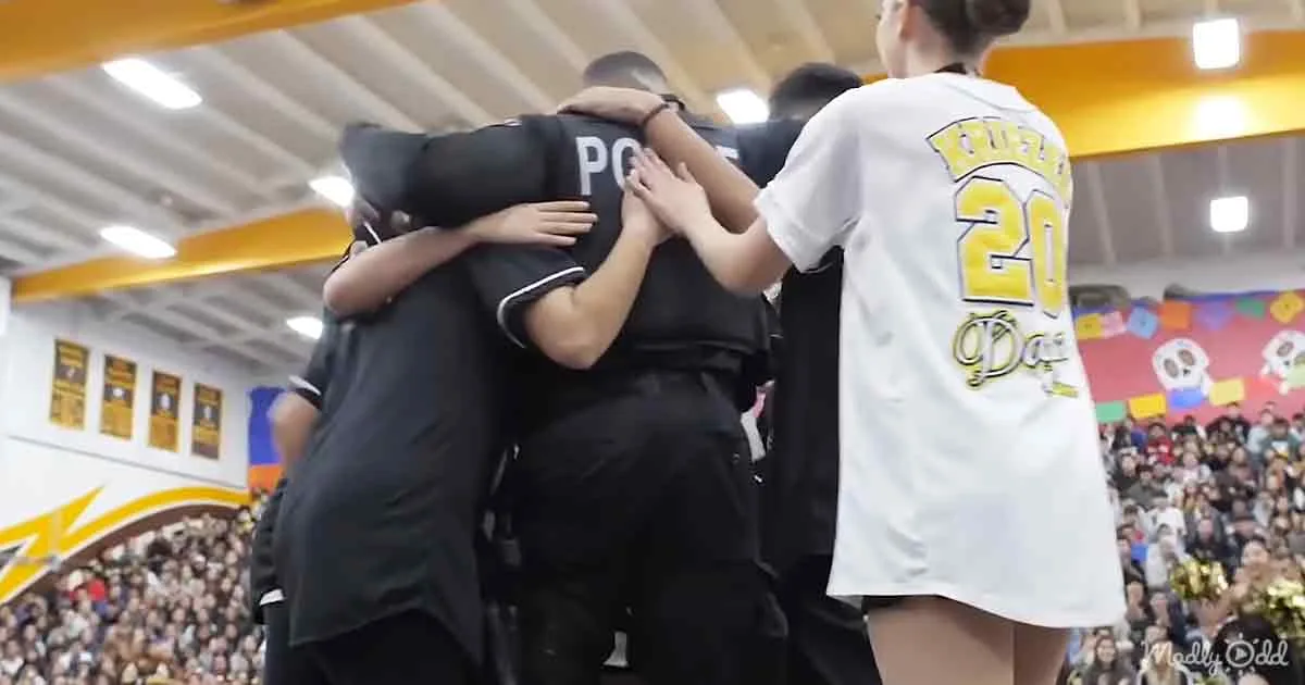 A group of people in sports attire huddle together in a gymnasium, celebrating or showing unity.