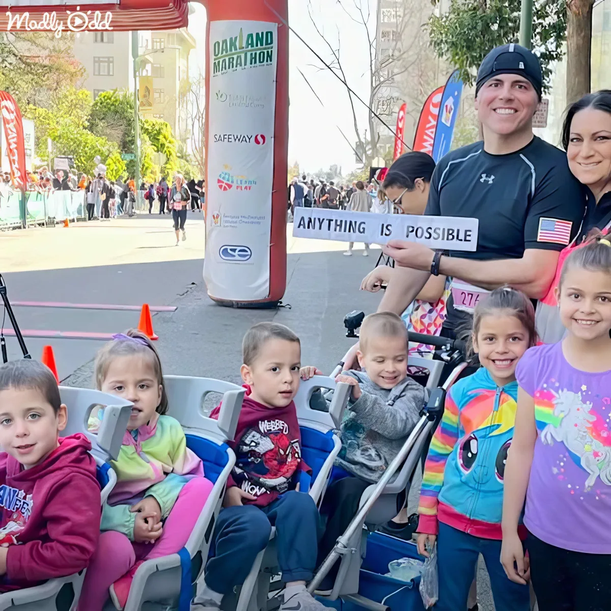 A family poses with a sign saying "Anything is Possible" at the Oakland Marathon.