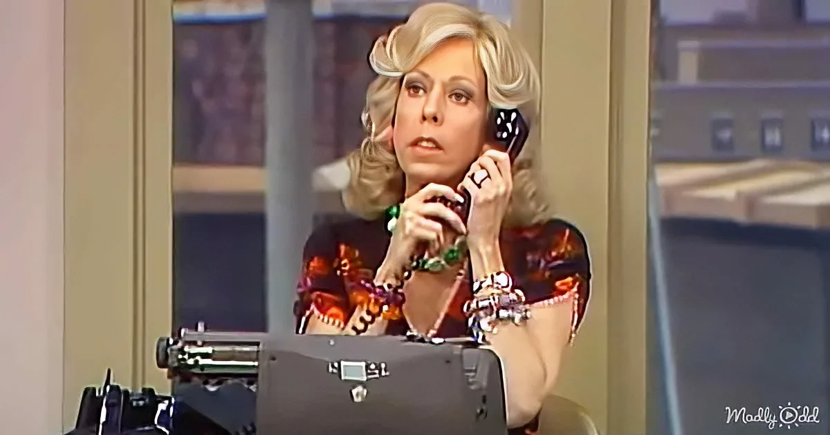 A woman with blonde hair and a colorful outfit is holding a phone to her ear, appearing to be in a conversation.