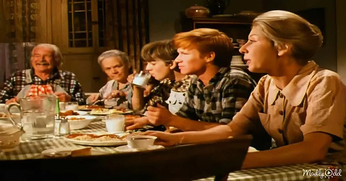 A family of six is gathered around a dining table, enjoying a meal together in a cozy, warmly lit room.