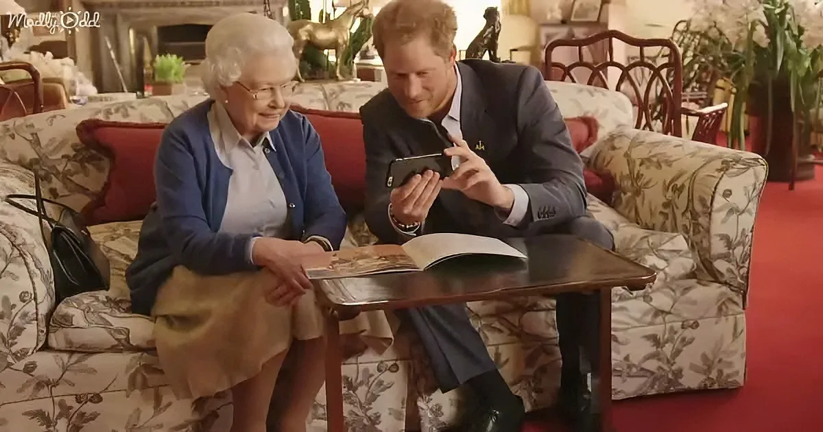 Prince Harry and Queen Elizabeth II sit on a floral-patterned couch, looking at a smartphone together.