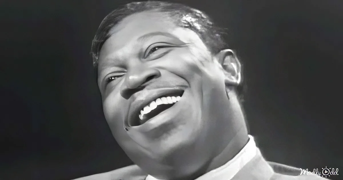 A smiling man in a white shirt, captured in a black and white photograph.