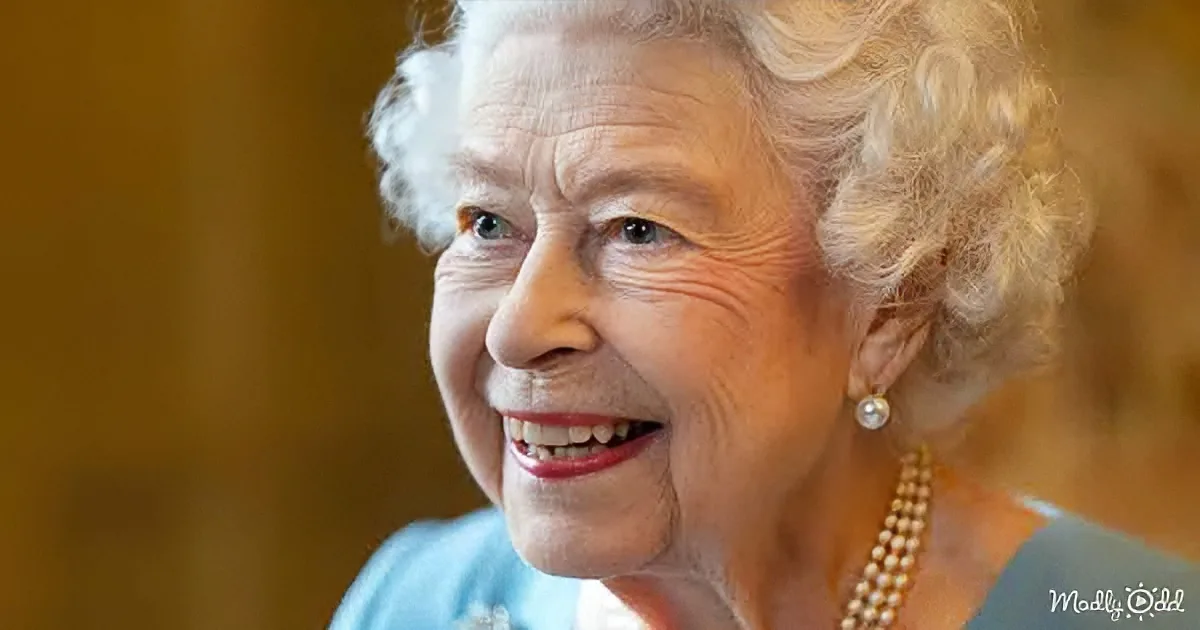 An elderly woman with white hair, wearing a pearl necklace and earrings, smiles warmly.