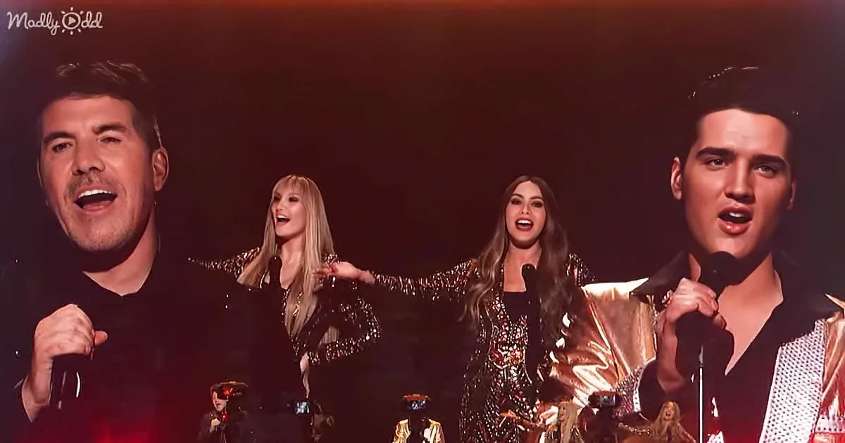 A group of performers, including a man in a black suit and a woman in a gold outfit, are singing on stage.