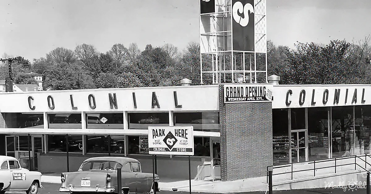 Colonial store grand opening sign with vintage cars and parking sign.