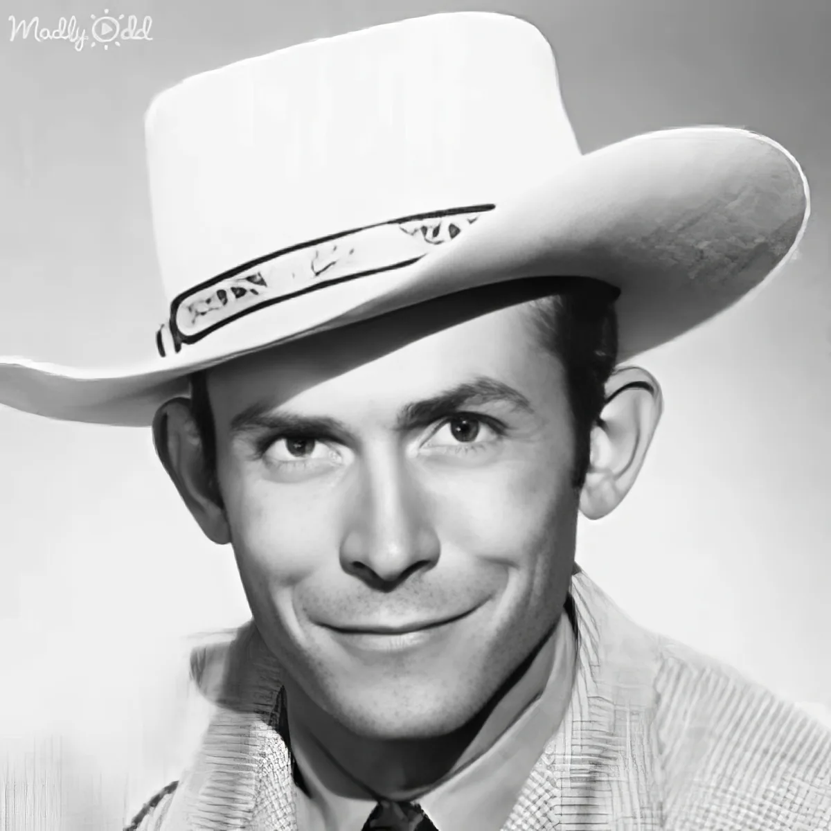 A man in a cowboy hat and suit, smiling, with a vintage, monochromatic look.