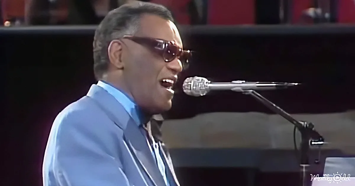 A man in a blue suit sings into a microphone, wearing sunglasses, with a piano in the background.