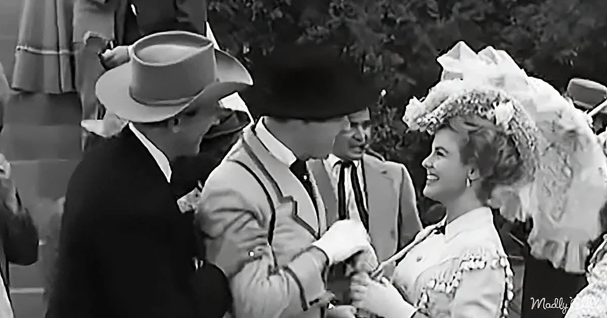 A man in a cowboy hat and a woman in a floral dress share a tender moment at a formal gathering.