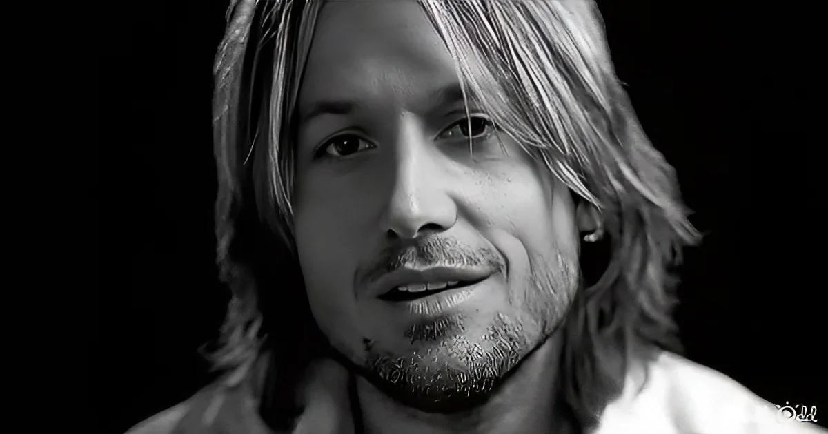A man with long hair and a beard, smiling slightly, in a black-and-white portrait.