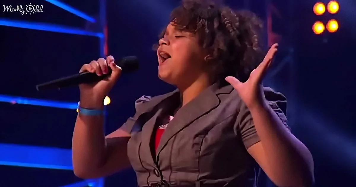 A woman sings passionately on stage, holding a microphone, with her eyes closed and hands raised.