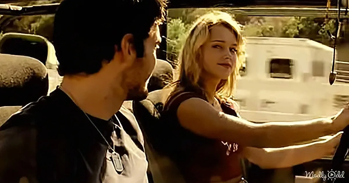 A woman in a red tank top aims a gun, while a man in a black shirt stands beside her, both in a tense outdoor setting.