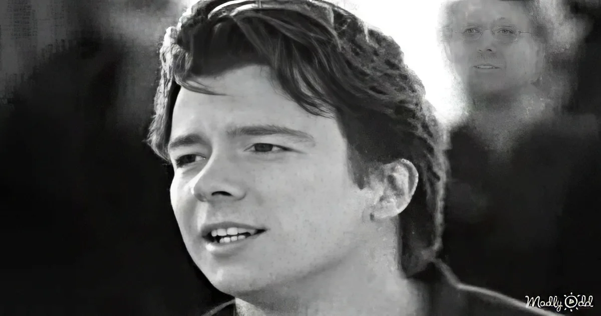 A smiling man with sunglasses on his head, wearing a dark shirt, in a black-and-white photo.