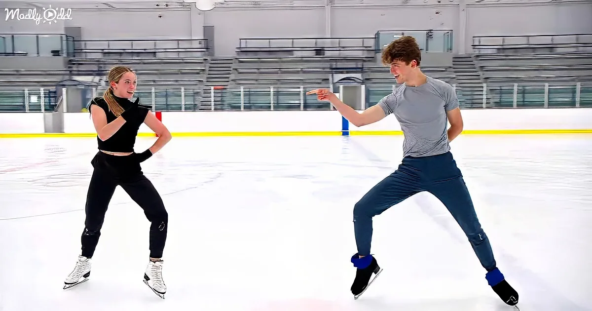 Two people skating on ice rink, one pointing, both smiling, wearing casual clothes.