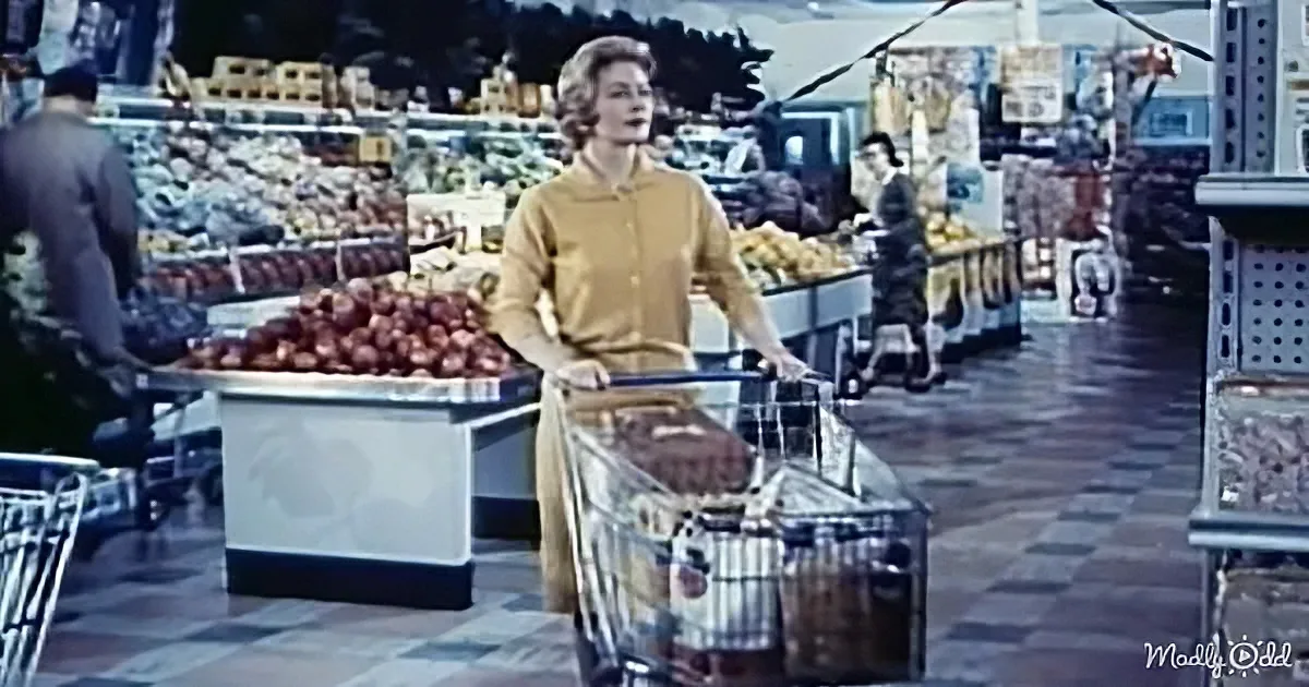 A woman in a yellow sweater pushes a shopping cart in a vintage grocery store with colorful produce and checkered floor.