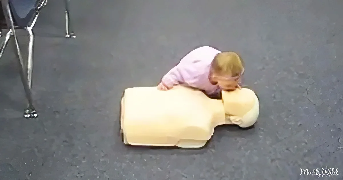 A child in a pink shirt is performing CPR on a yellow mannequin.